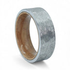 Close-up of tungsten ring with whiskey barrel wood interior showing natural grain and rustic forged texture
