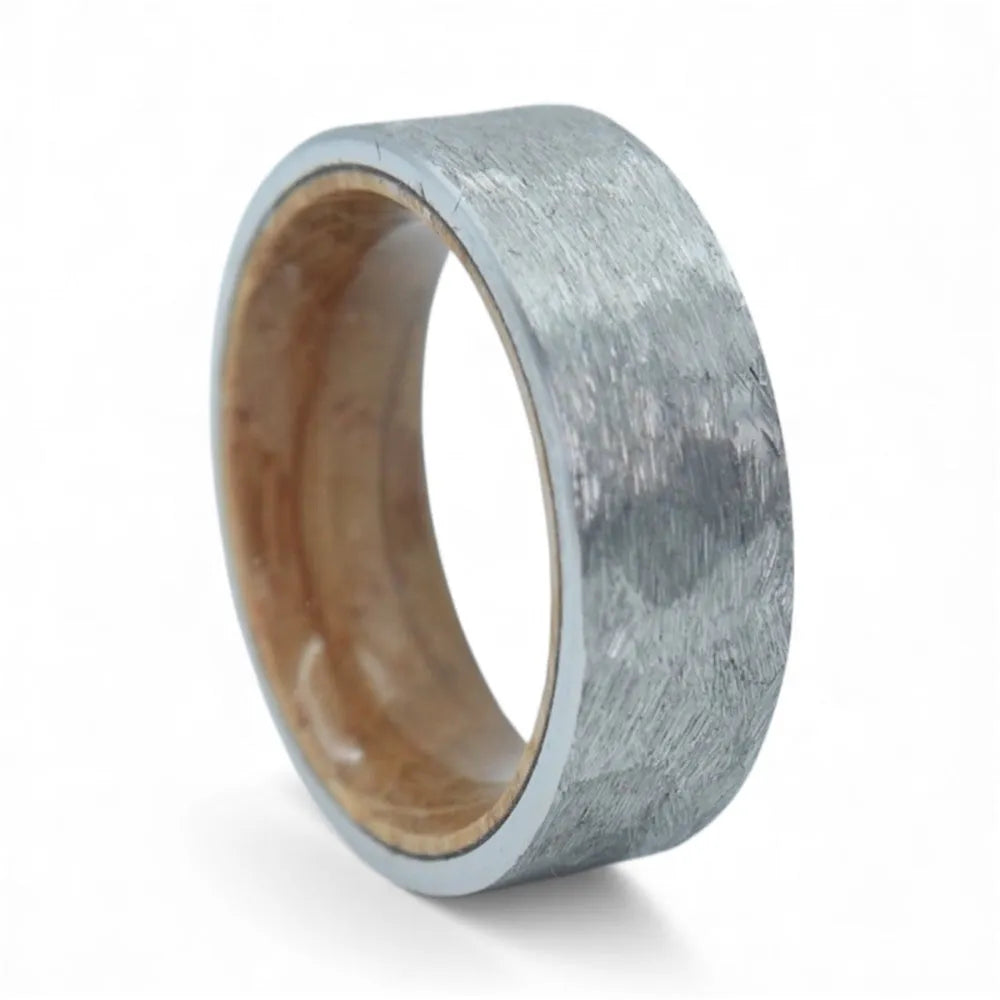 Close-up of tungsten ring with whiskey barrel wood interior showing natural grain and rustic forged texture