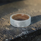 Close-up of tungsten ring with whiskey barrel wood interior showing natural grain and rustic forged texture