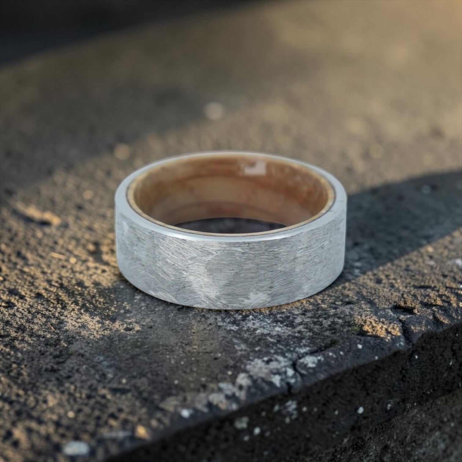 Close-up of tungsten ring with whiskey barrel wood interior showing natural grain and rustic forged texture