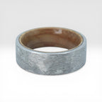 Close-up of tungsten ring with whiskey barrel wood interior showing natural grain and rustic forged texture
